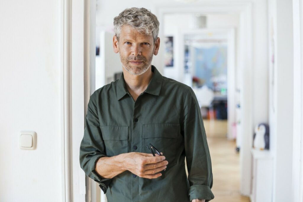 Portrait of mature man with grey hair and stubble at home